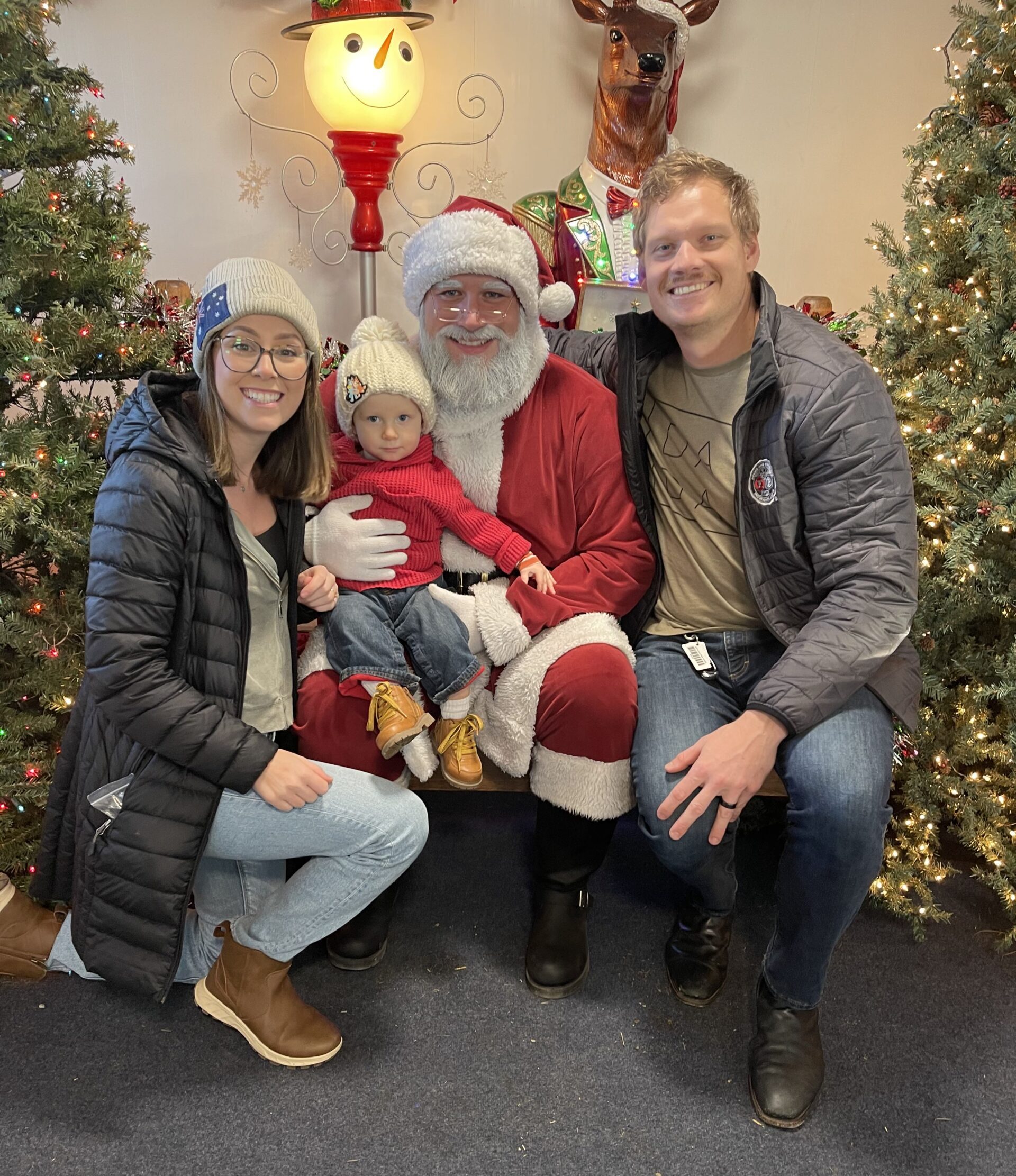 A photo of Julius Van Rooyen, his wife, and his young child posed and smiling at the camera with Santa