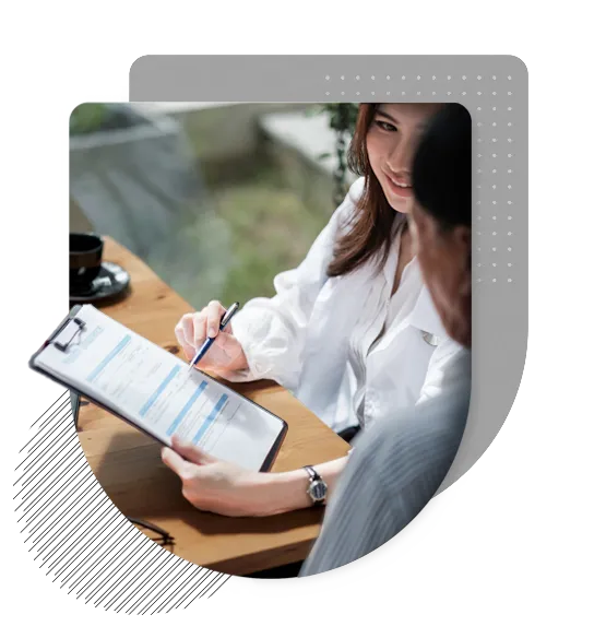 A closeup of a life insurance agent walking a client through a clipboard of paperwork, helping them understand the contents of the form.